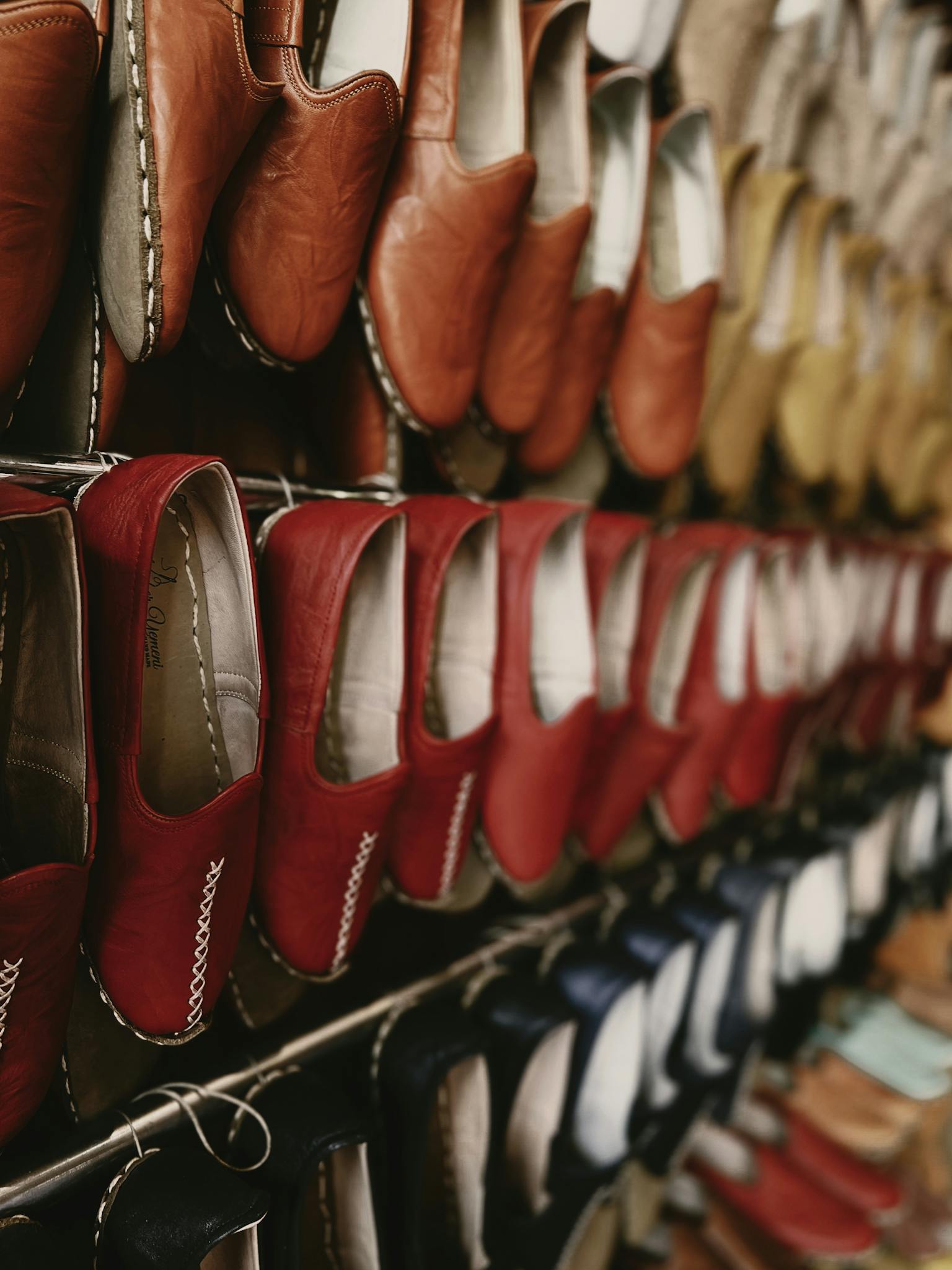 Close-up view of various leather shoes hanging in a retail display showcasing vibrant colors.