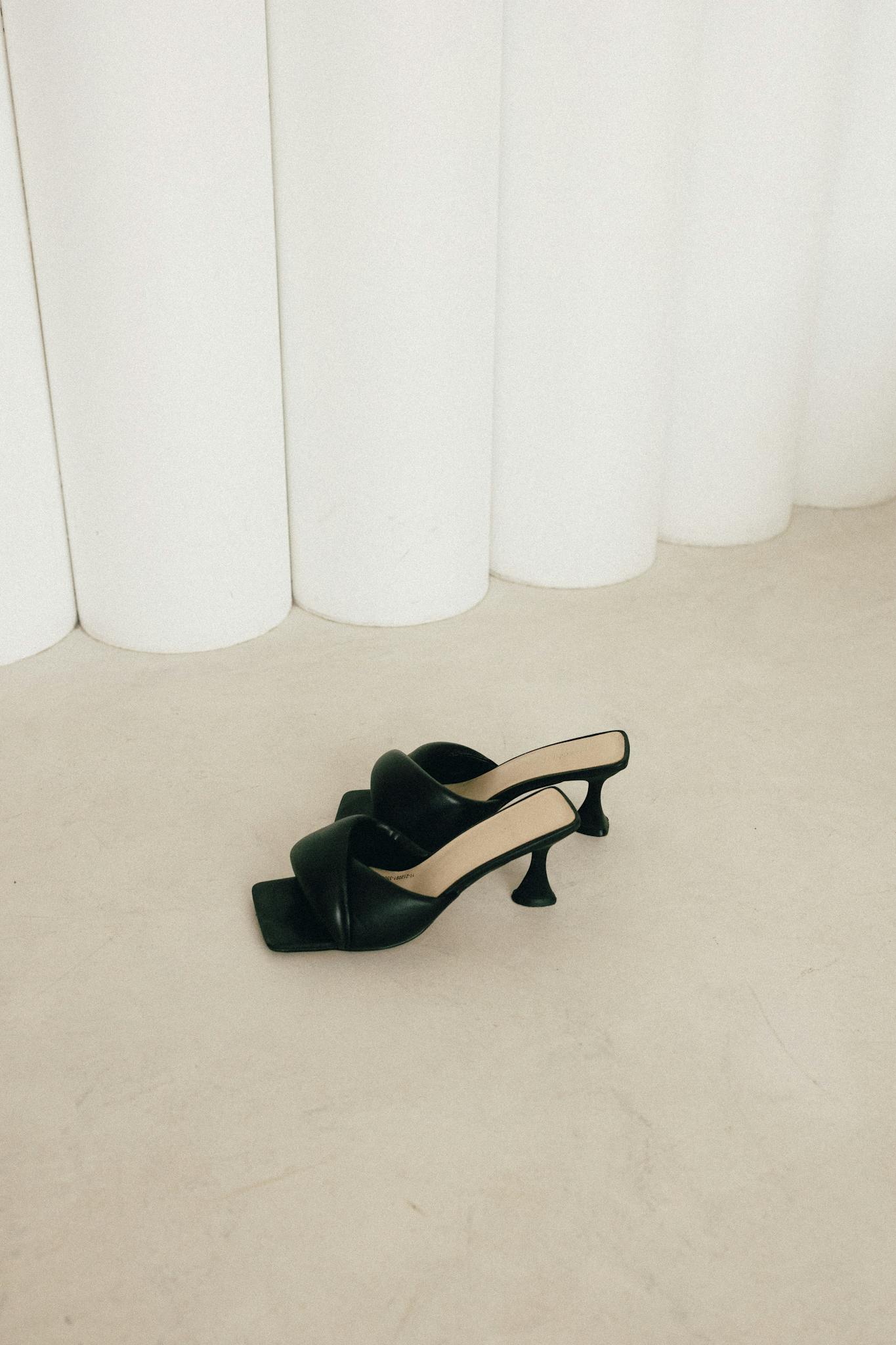 Stylish black high-heeled shoes on a minimalist white and beige backdrop.